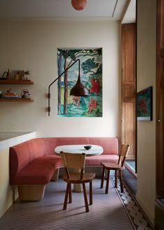 a painting hangs above a table with chairs and a bench in front of it on the wall