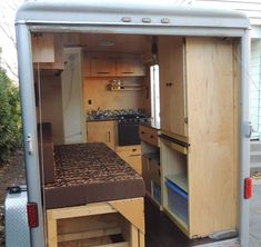 the interior of an rv with its bed pulled out and storage compartment open on the side