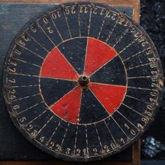 an old dart board with numbers and arrows on the back side, in front of a black background