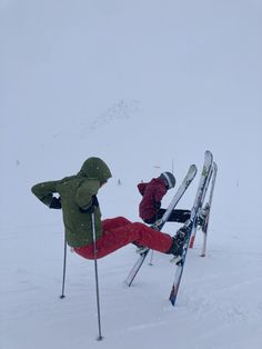 two people on skis in the snow with their feet propped up against each other