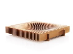 a wooden object with wavy lines on the sides and bottom, sitting on a white surface