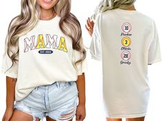 a woman wearing a white shirt with the word mama on it and two other women's shirts behind her