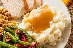 a white plate topped with meat, mashed potatoes and green beans