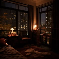 a dimly lit room with a view of the city at night from it's windows