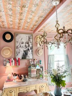 a room with pink walls and pictures on the wall, chandelier hanging from ceiling