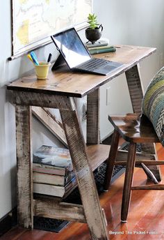 a laptop computer sitting on top of a wooden desk next to a chair and window