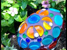 a colorful rock sitting in the middle of some flowers