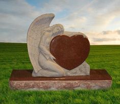 an angel holding a heart statue in the middle of a field