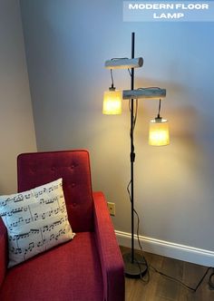 a red chair sitting next to a lamp on top of a wooden floor