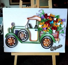 a card with an old fashioned car and flowers on the front, sitting on a easel