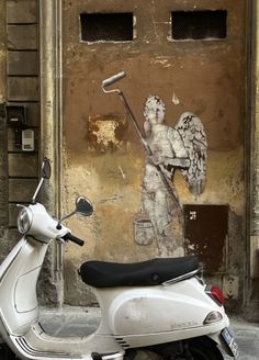 a scooter parked in front of a wall with an angel painting on it