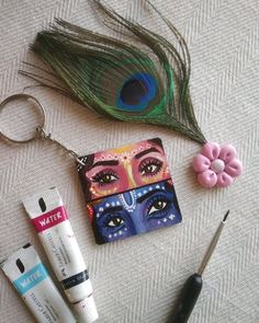 some items are laying out on the floor next to a peacock feather and eyeliners