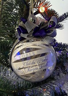 a glass ornament hanging from the top of a christmas tree with purple ribbon