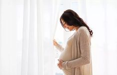 a pregnant woman standing in front of a window