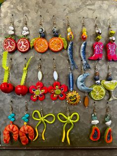 there are many different earrings hanging on the wall next to each other, including oranges and lemons