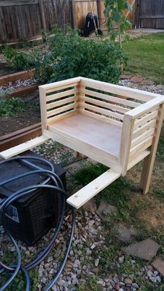 a wooden bench sitting in the middle of a yard next to a garden hose holder