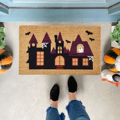 a person standing in front of a halloween door mat