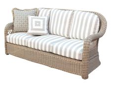 a wicker couch with blue and white striped pillows on it's armrests