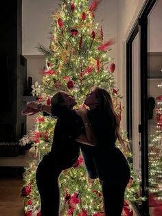 two women standing in front of a christmas tree