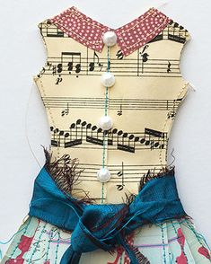 a dress made out of fabric with musical notes on it and a blue ribbon around the waist