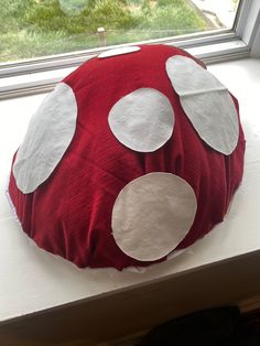 a red and white pillow sitting on top of a window sill