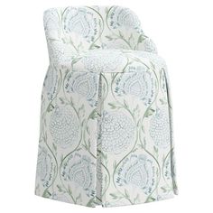 an upholstered chair with blue and green flowers on the back, in front of a white background