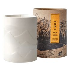 a white ceramic candle holder next to a box with an image of mountains on it