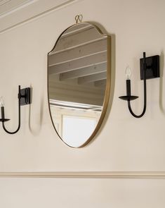 two black sconces and a mirror on the wall