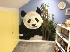 a panda bear mural on the wall of a children's room with bookshelves