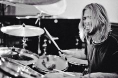 a man with long hair is playing drums