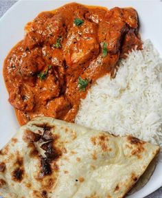 a white plate topped with rice and meat next to a tortilla covered in sauce