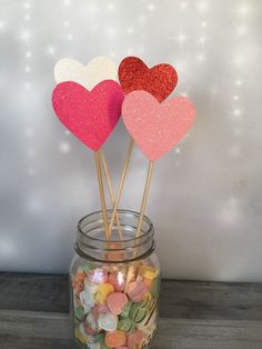 three heart shaped lollipop sticks in a jar filled with candy