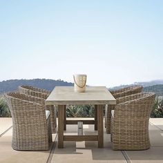 an outdoor table with chairs and a vase on it