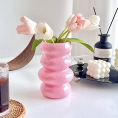 a pink vase filled with flowers on top of a table next to a candle holder