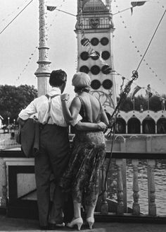 an old photo of two people standing on a pier