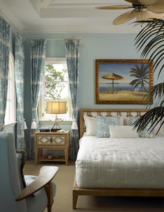 a bedroom with blue walls and white bedding, palm tree in the foreground