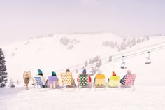 four lawn chairs are lined up in the snow