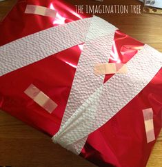 a red bag sitting on top of a wooden table covered in tape and paper strips