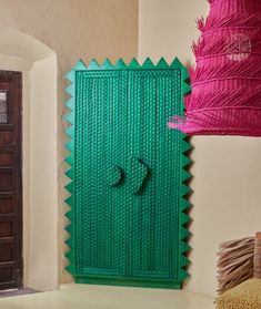 a green door with a pink lamp hanging from it's side in a room