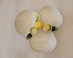 three lemons and two limes on a white platter with green trim around the edges