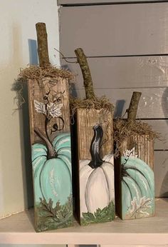 three pumpkins painted on wooden blocks sitting on top of a shelf next to each other