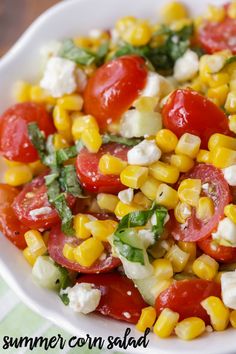 a white bowl filled with corn, tomatoes and feta cheese on top of a table