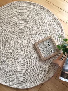 a white rug with a wooden frame on top of it next to a potted plant