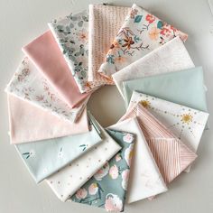 a bunch of different types of fabric on a white tablecloth with flowers and leaves