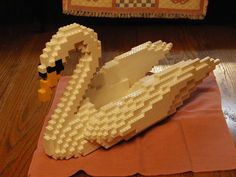 a lego model of a swan sitting on top of a piece of paper next to a rug