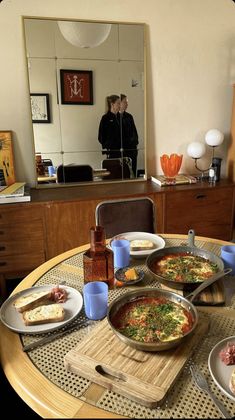 a table topped with lots of food on top of a wooden table next to a mirror