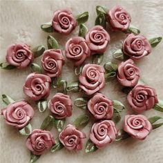 small pink roses with green leaves on a white surface, arranged in the shape of a circle