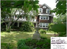 a large house sitting in the middle of a lush green yard with trees and bushes