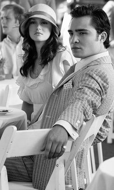 a man and woman sitting next to each other at a table with white clothed tables