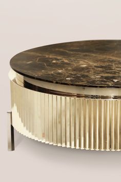 a round coffee table with a black marble top and gold metal trim around the base